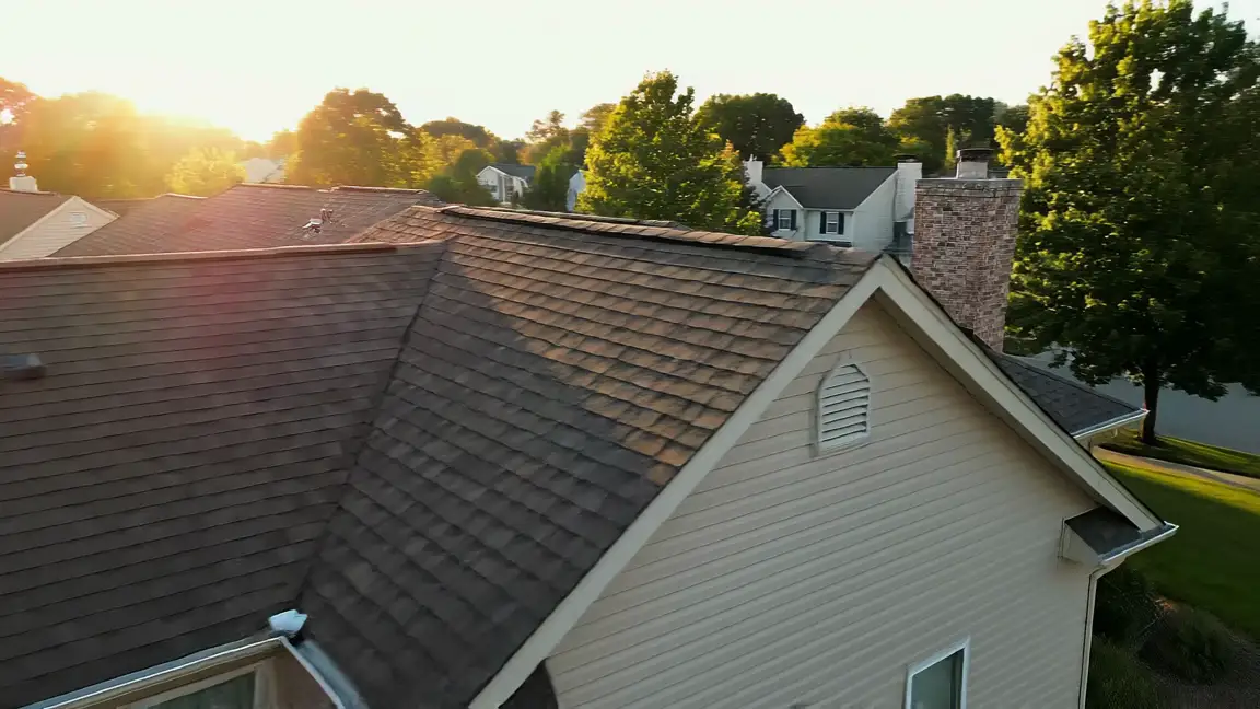 A slow aerial drift across the rooflines of an American suburb at golden hour